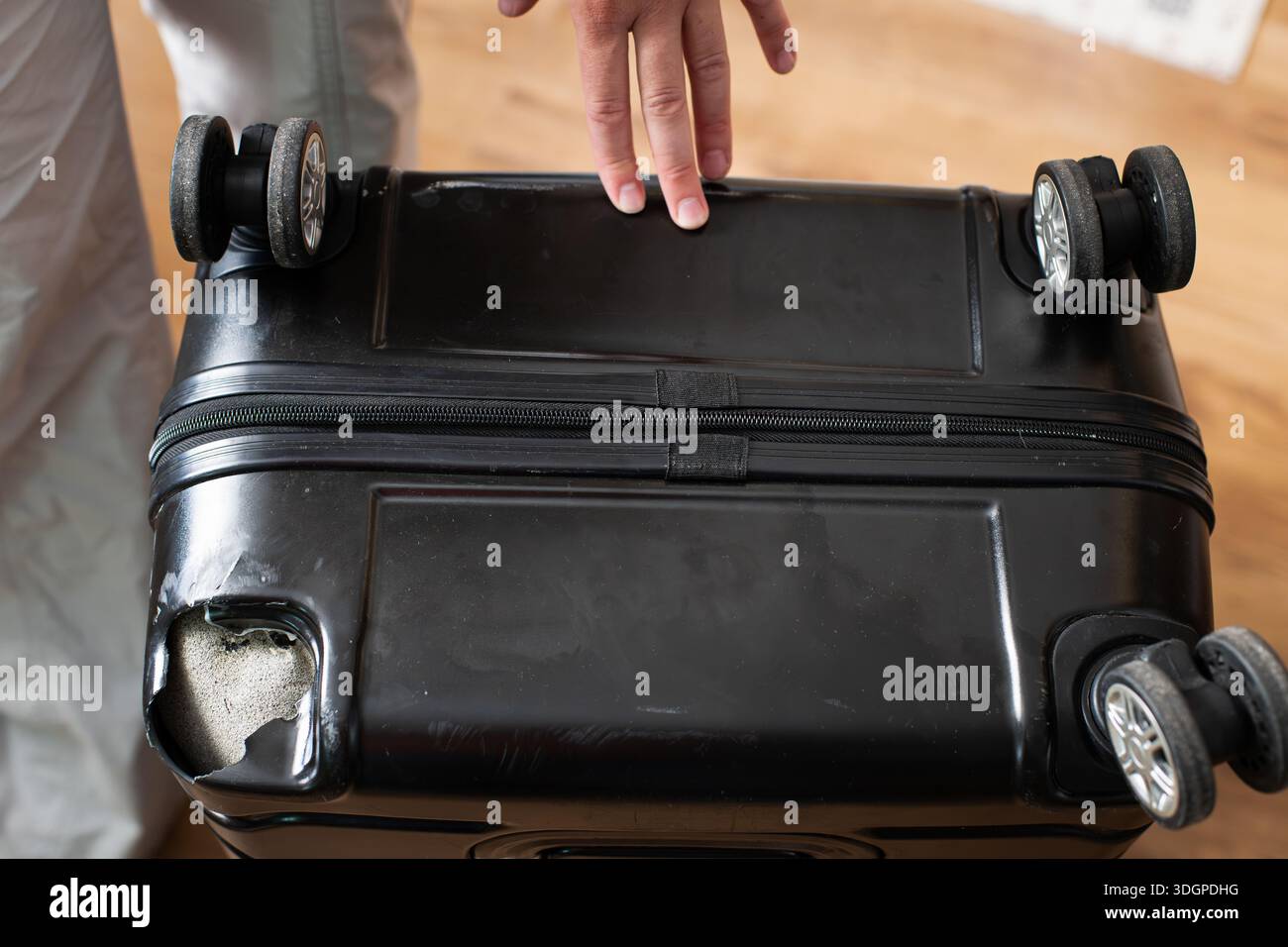 Valigia nera rotta con angolo danneggiato che mostra l'impatto di una cattiva gestione all'aeroporto Foto Stock