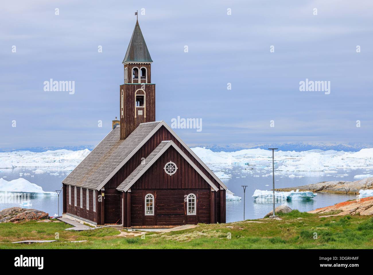 pittoresco paesaggio di chiesa in legno artico sul lungomare di ilulissat in groenlandia di fronte al mare coperto di iceberg Foto Stock