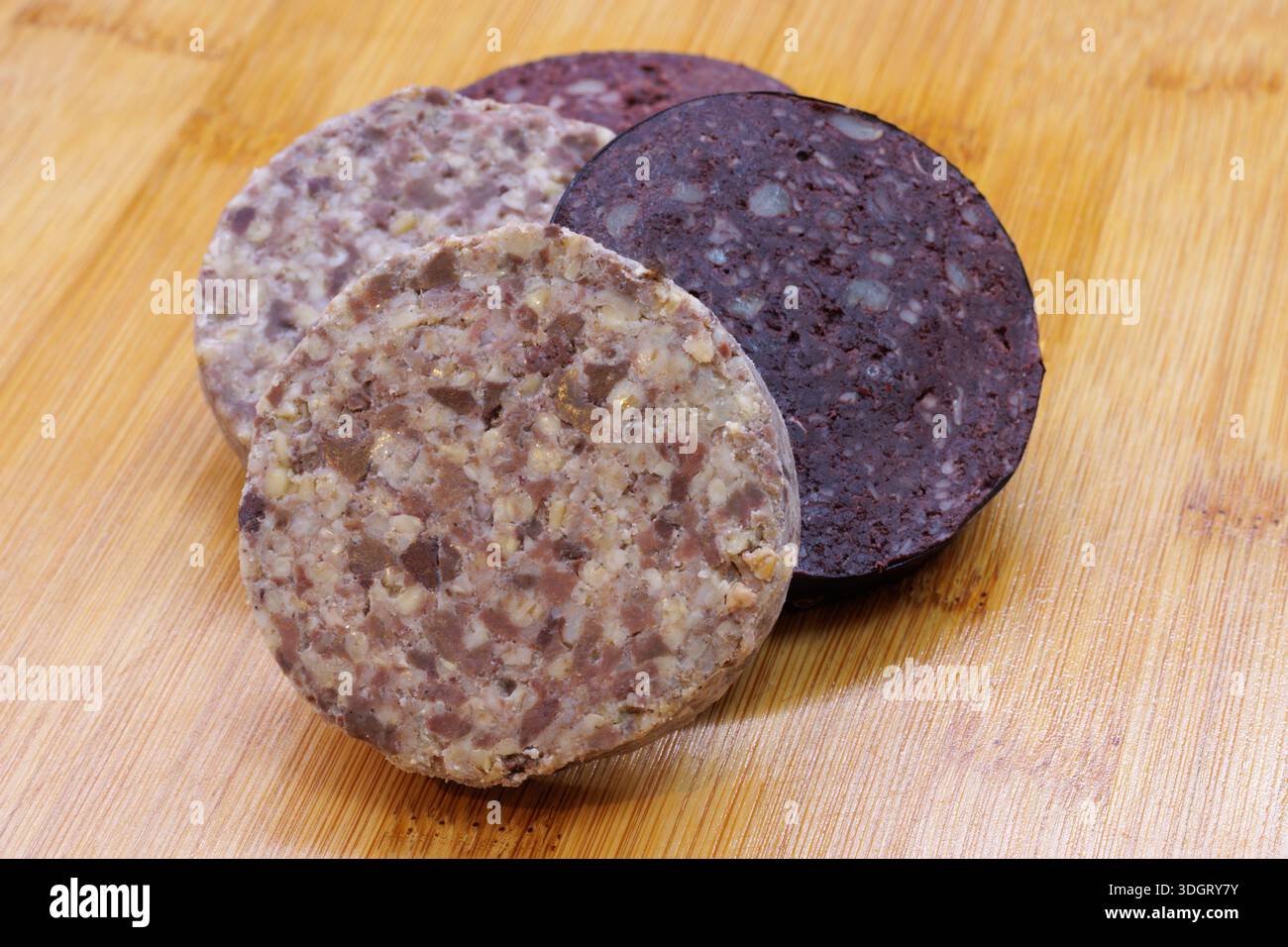 Fette crude di salsiccia e haggis su fondo di legno Foto Stock