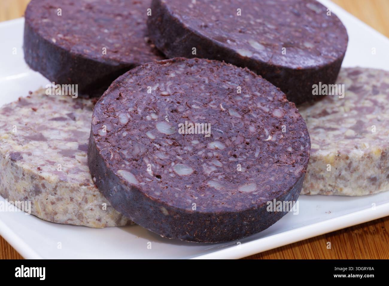 Fette rotonde di budino nero e haggis su piatto bianco Foto Stock