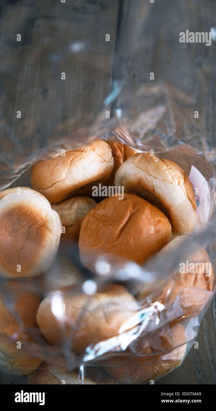 Panini morbidi in un sacchetto di plastica, appena sfornati con una superficie marrone dorata, semplici panifici di tutti i giorni catturati dalla calda luce naturale Foto Stock