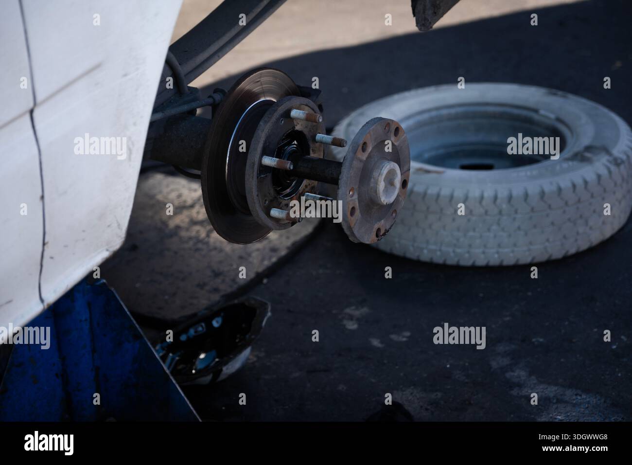 Disco del freno per auto e mozzo della ruota esposti durante la manutenzione del veicolo in un'officina di riparazione con pneumatico rimosso Foto Stock