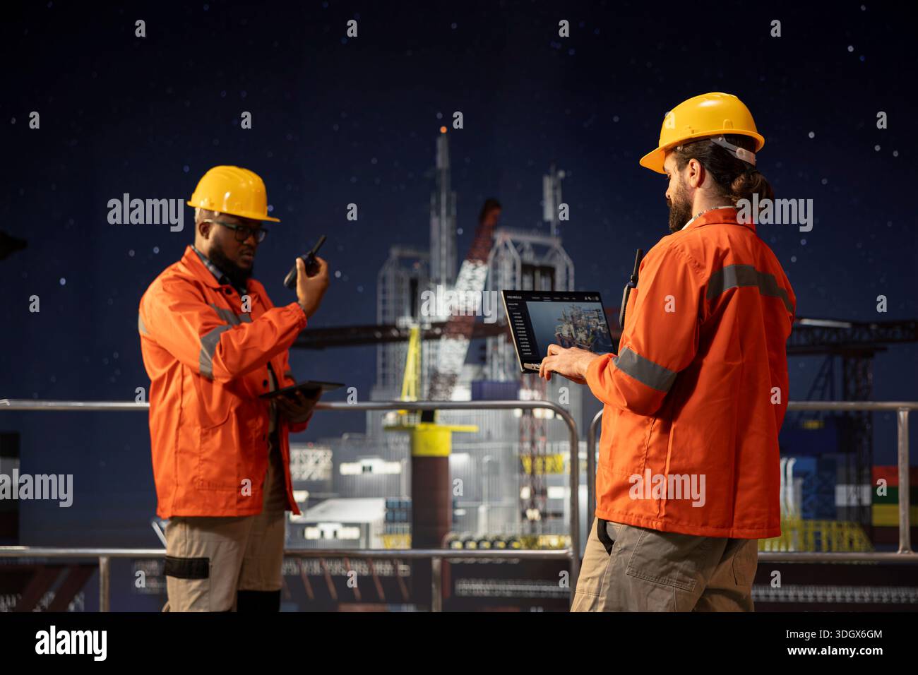 Il dipendente della piattaforma offshore utilizza un laptop sul ponte della piattaforma petrolifera accanto al collega che utilizza walkie talkie a tarda notte. Ingegnere chiatta che esamina le operazioni energetiche su un carro di perforazione accanto a un collega afroamericano Foto Stock