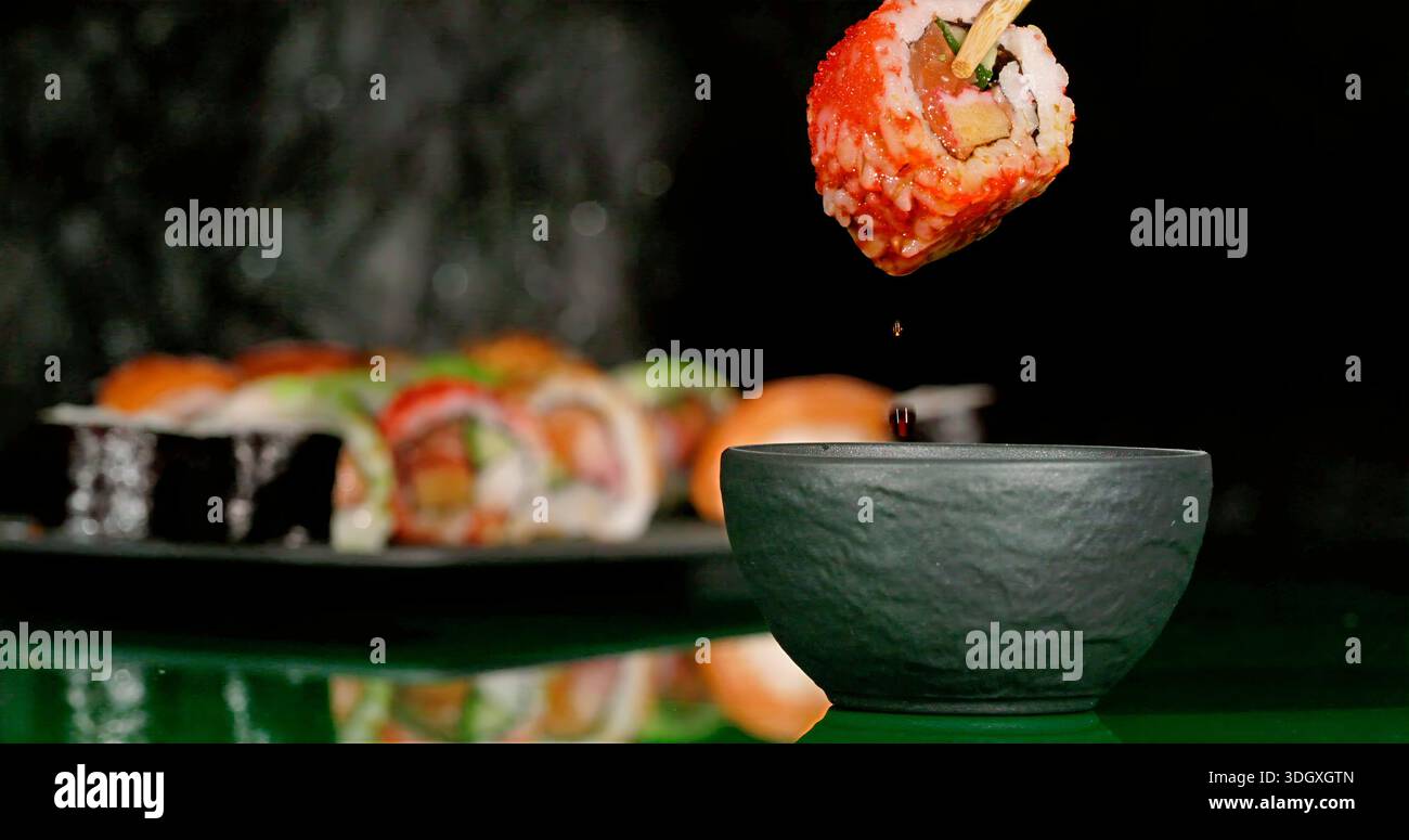 Immergere il sushi al salmone nella ciotola della salsa di soia, fare una scena ravvicinata del salmone nella ciotola della salsa di soia Foto Stock