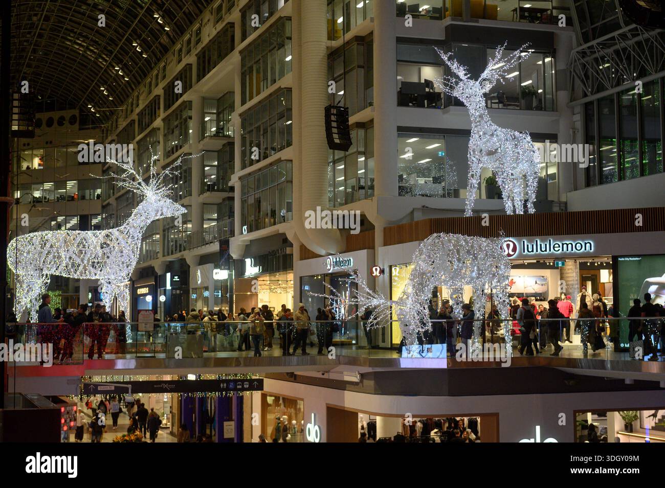 Toronto, ON, Canada - 24 dicembre 2025: Sculture di renne illuminate che decorano gli interni del centro commerciale multilivello, attirando le persone a guardare e fare shopping Foto Stock