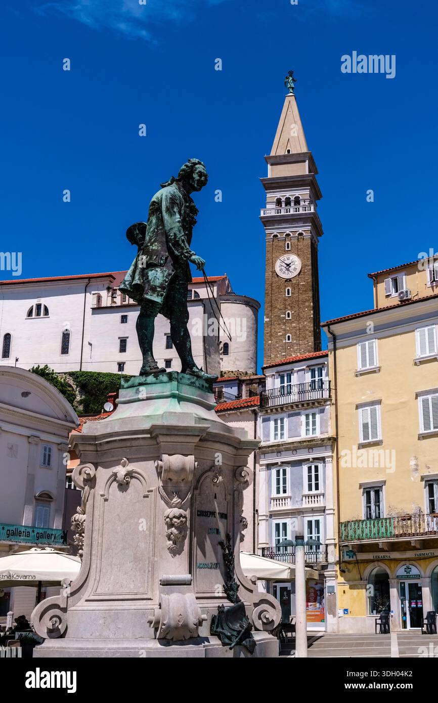 Statua in bronzo di Giuseppe Tartini su Piazza centrale Tartini con la Chiesa Parrocchiale di San Giorgio e il suo campanile in stile veneziano in lontananza. Foto Stock