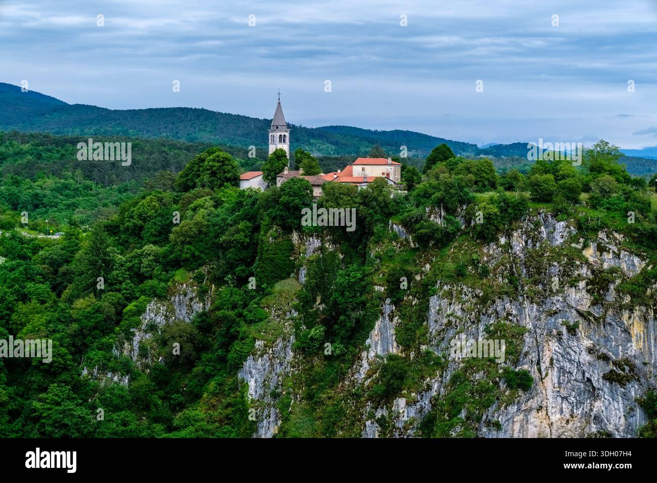 Il villaggio di Skocjan e la chiesa di San Canziano, situata su una scogliera rocciosa circondata da una fitta foresta. Foto Stock