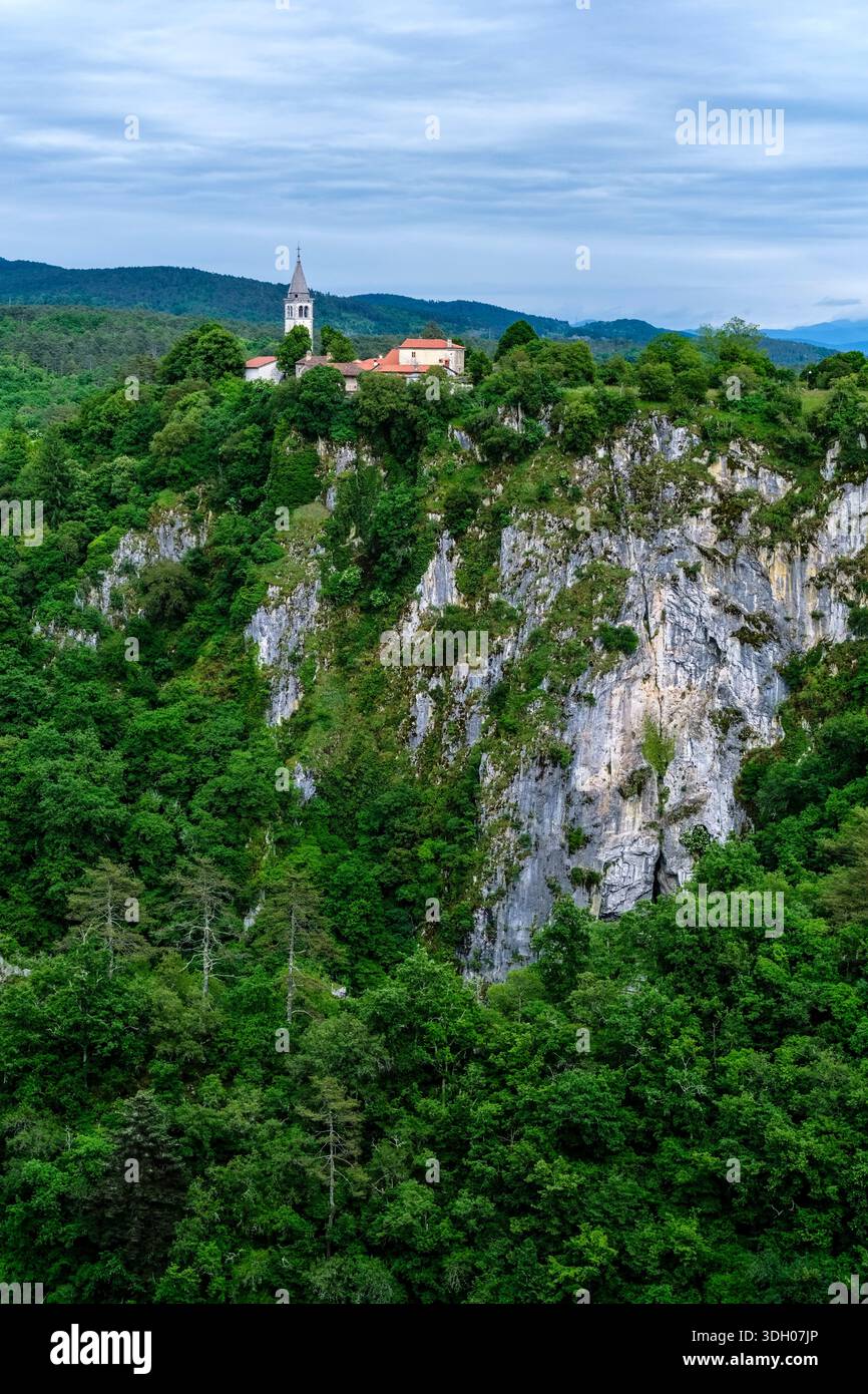 Il villaggio di Skocjan e la chiesa di San Canziano, situata su una scogliera rocciosa circondata da una fitta foresta. Foto Stock