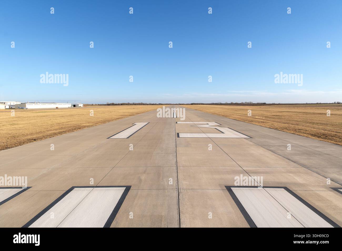 Pista vuota 13 che si estende attraverso un campo di aviazione pianeggiante e rurale Foto Stock