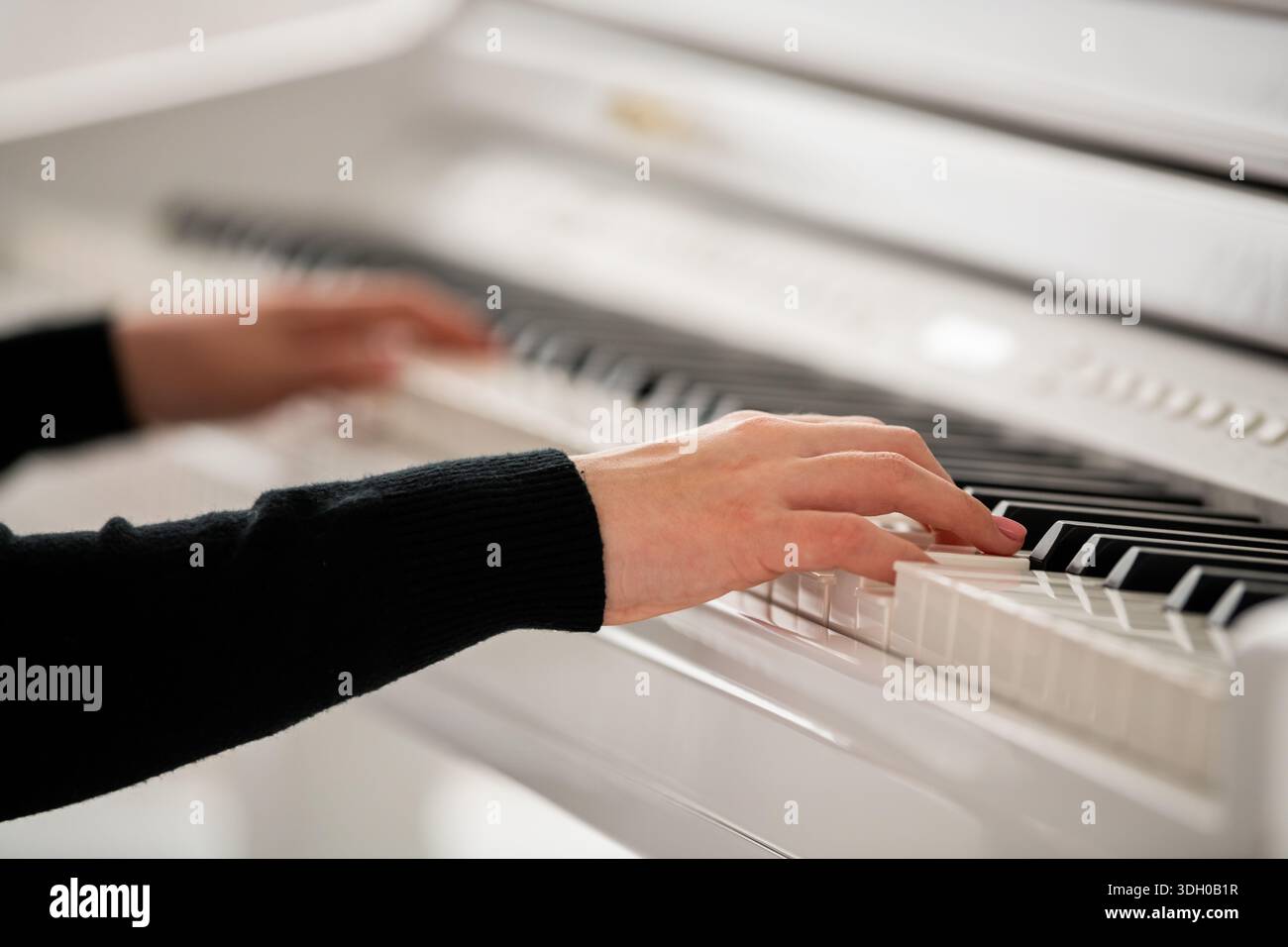 mani di un musicista adolescente su tastiera di pianoforte a coda bianco. Foto Stock