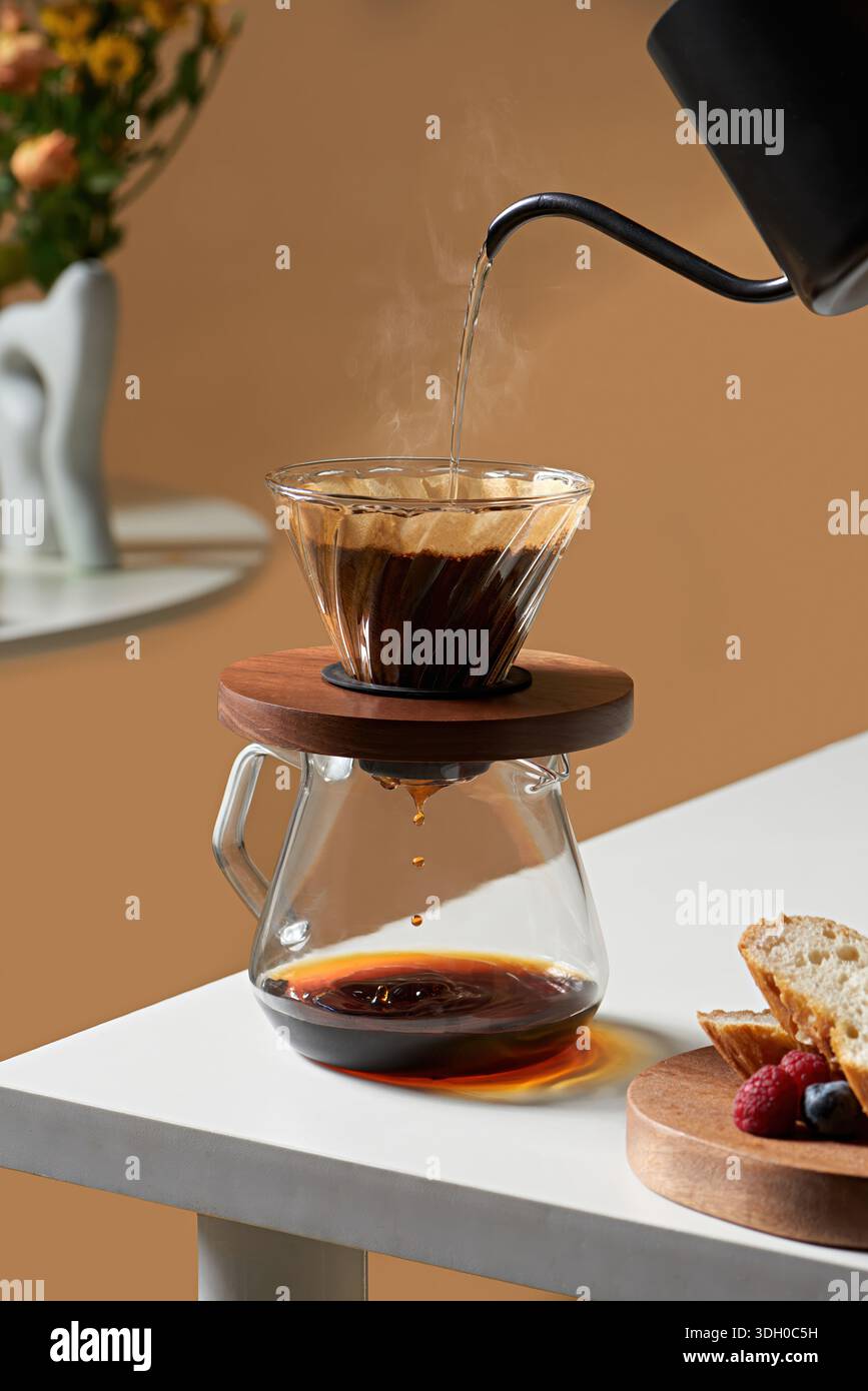 Versare acqua calda nel gocciolatore di vetro per erogare manualmente il caffè in modo professionale Foto Stock