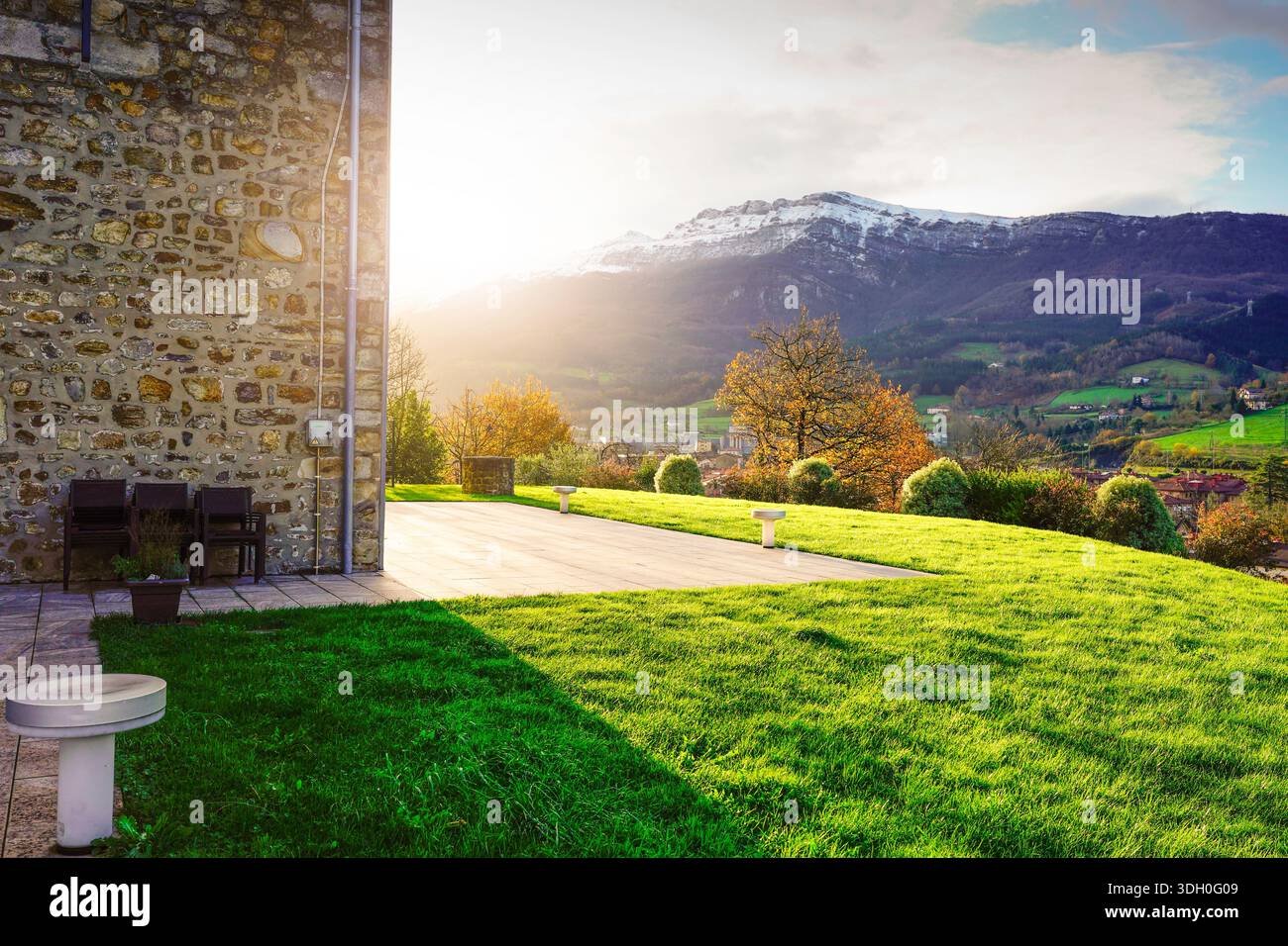 Paesaggio di campagna illuminato dal sole con prato verde, terrazza in pietra e valle di montagna in autunno. Vita rurale tranquilla, ambiente naturale. Foto Stock