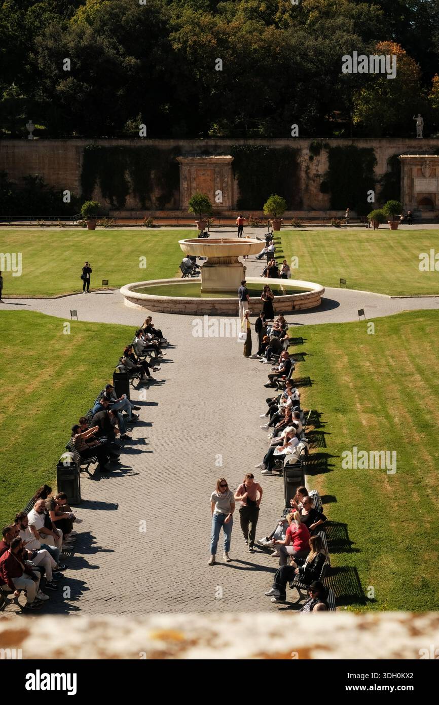 I visitatori si rilassano nel cortile della Pigna (cortile della Pigna) a città del Vaticano durante una giornata di sole. Foto Stock