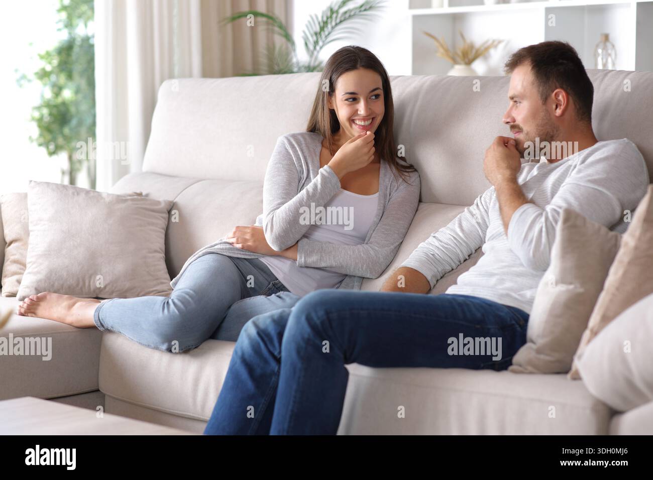 Una coppia felice che si incontra e mostra complicità che copia il comportamento seduto su un divano a casa Foto Stock