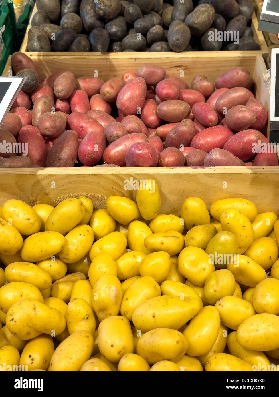 Tre tipi di patate esposti in una bancarella di mercato, tra cui patate rosse Laura, patate viola e patate gialle. Verdure biologiche fresche per condire Foto Stock