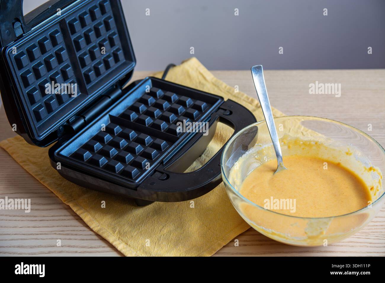 Macchina elettrica per waffle con un recipiente di impasto per waffle pronto per la cottura. Cucina casalinga per preparare waffle freschi. Ideale per la colazione, piatti fatti in casa Foto Stock