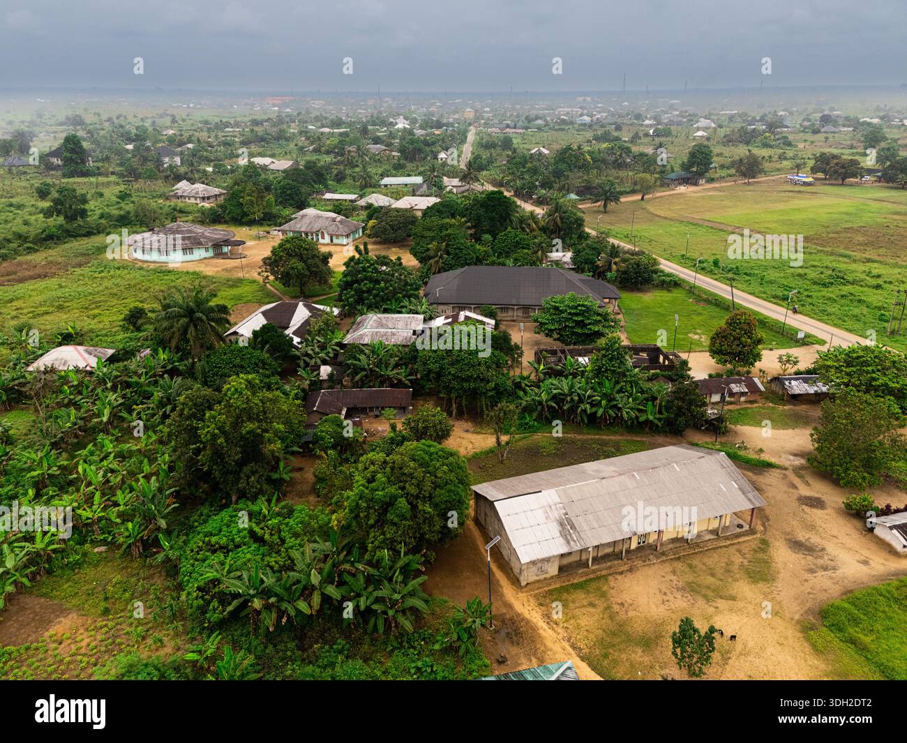 Vista aerea del villaggio con edifici sparsi tra la vegetazione lussureggiante sotto il cielo coperto, Khana, Rivers, Nigeria. Foto Stock