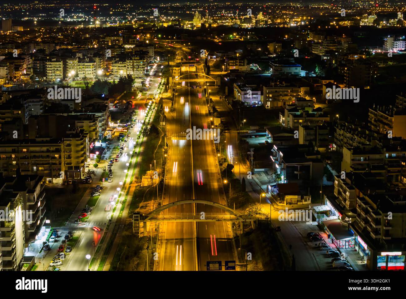 Salonicco, Grecia. Le riprese aeree notturne catturano la circonvallazione illuminata e i quartieri occidentali, con percorsi leggeri dai veicoli e dal denso urb Foto Stock