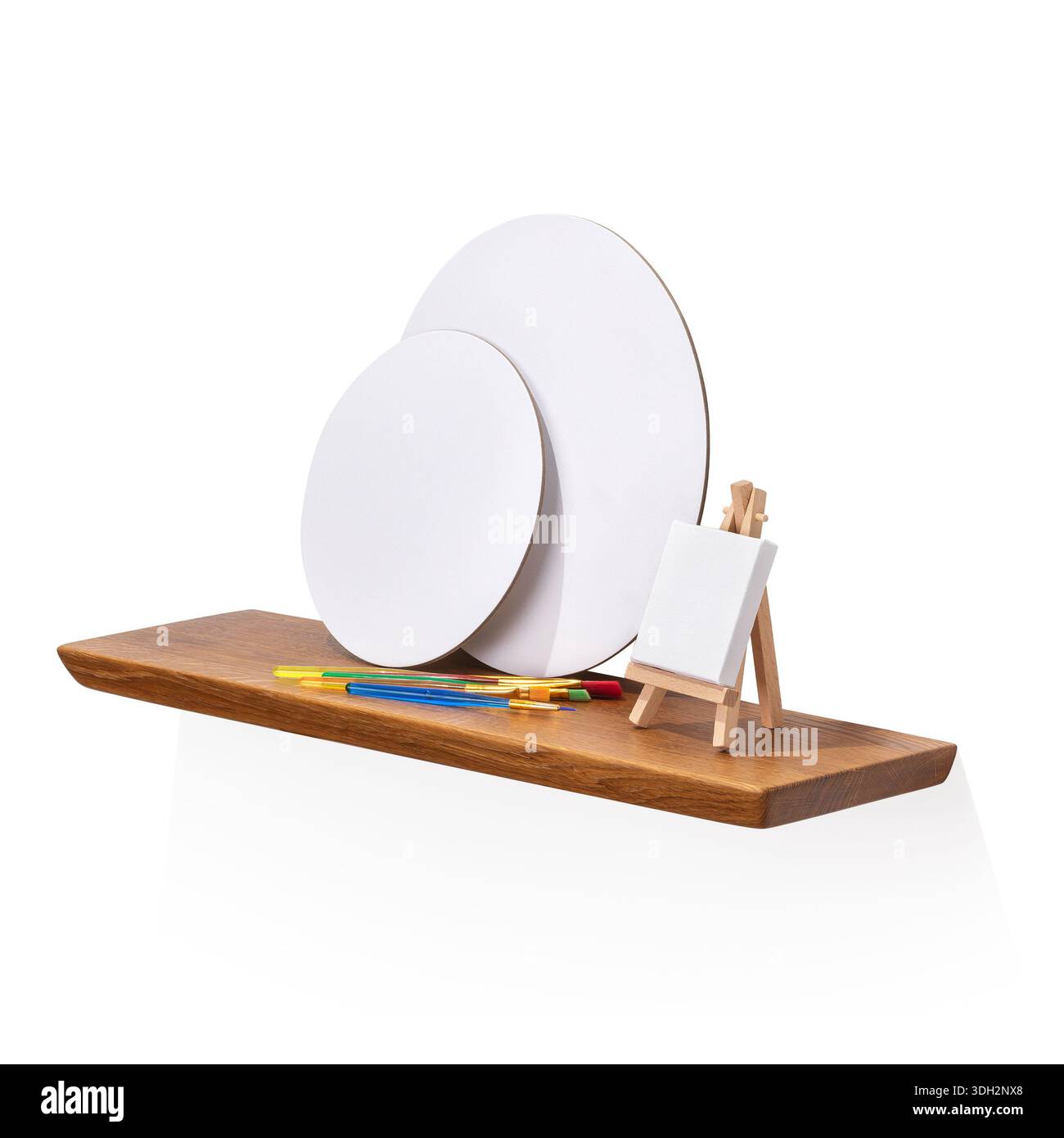 Pennelli e tele vuote su un ripiano in legno di quercia, isolato su sfondo bianco, fotografia autentica, non generata dall'intelligenza artificiale Foto Stock