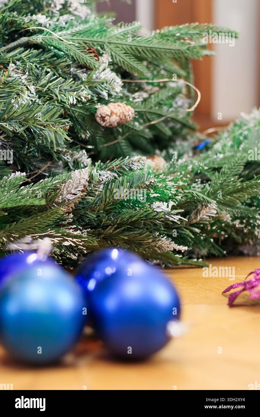 Lussureggianti rami di abete artificiale spolverati di neve finta e decorati con pineconi, abbinati a baule in vetro blu appese e dettagli floreali viola su una W Foto Stock