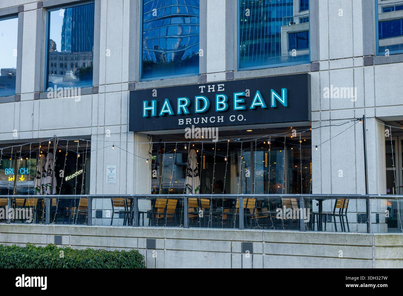 Vancouver, Canada - 18 gennaio 2026: Esterno del ristorante Hard Bean Brunch Co. Con insegne al neon, luci a corda e area salotto nel patio Foto Stock