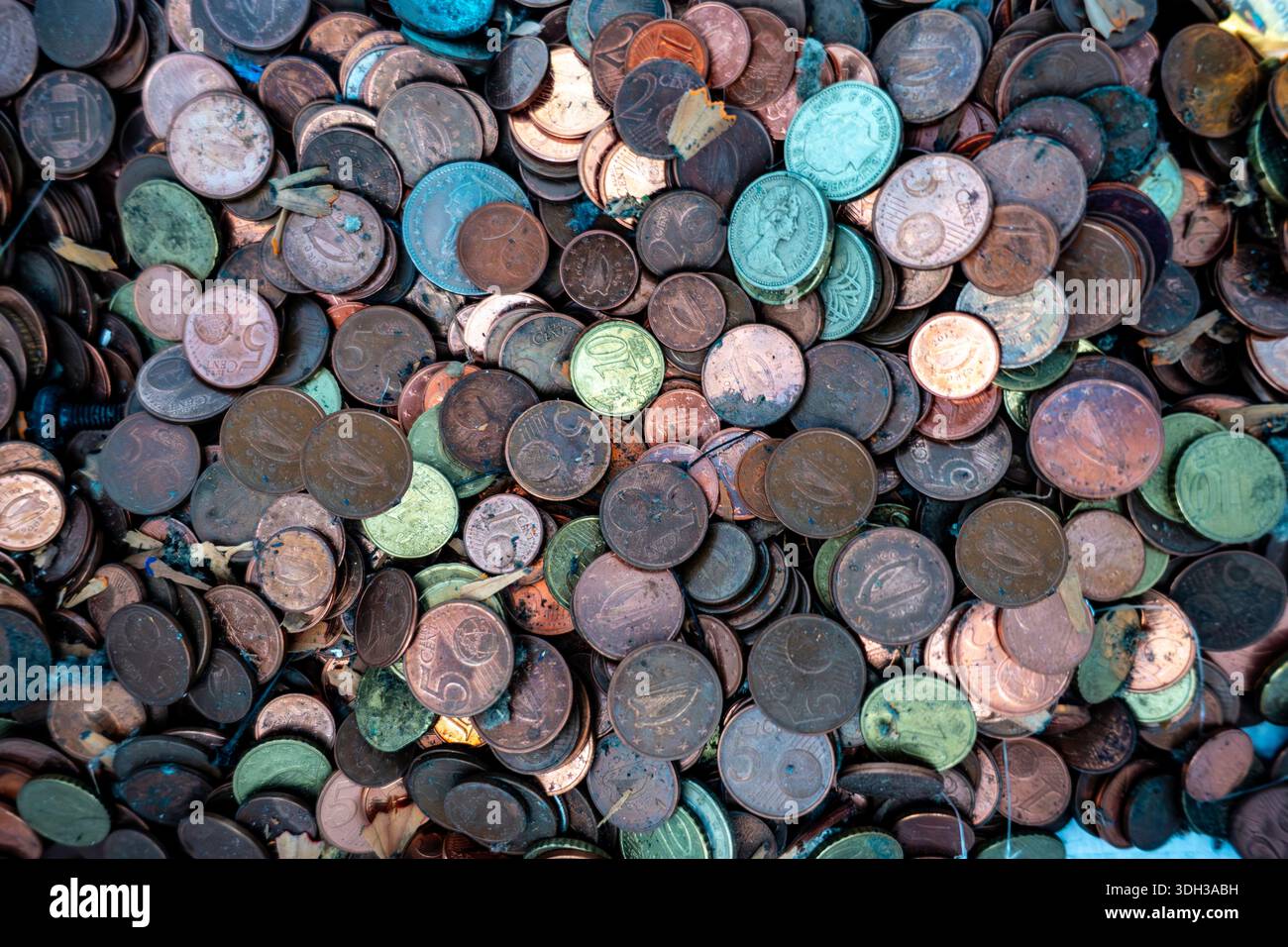 Una vista panoramica dettagliata di un enorme mucchio di monete in euro sporche e macchiate, mescolate con detriti, che illustrano temi di ricchezza, disordine e valuta. Foto Stock