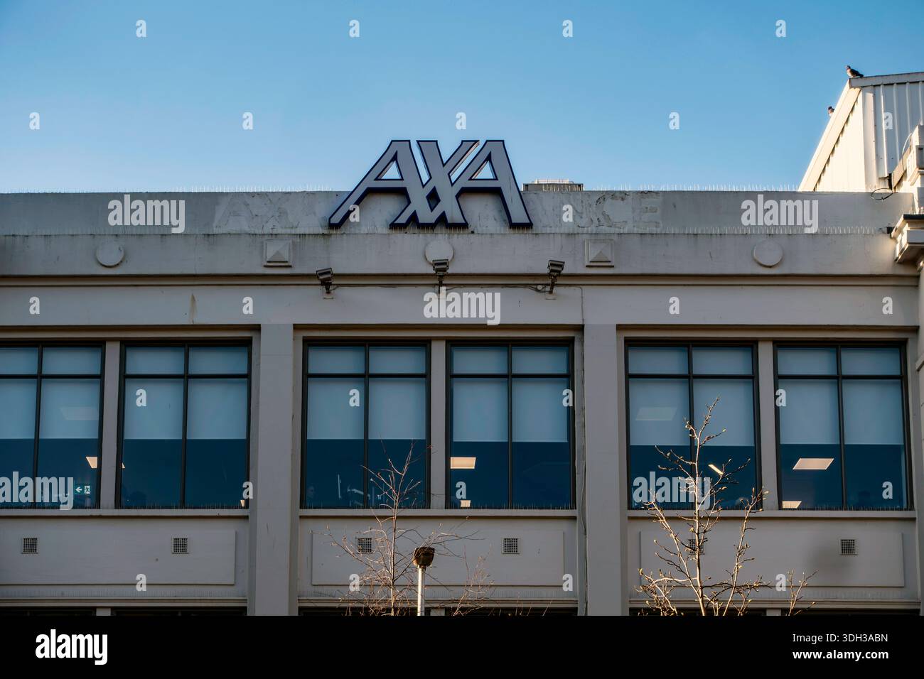 Il logo blu e bianco AXA Insurance è montato in cima a un edificio di uffici aziendali a Dublino, contro un cielo azzurro chiaro e luminoso. Foto Stock