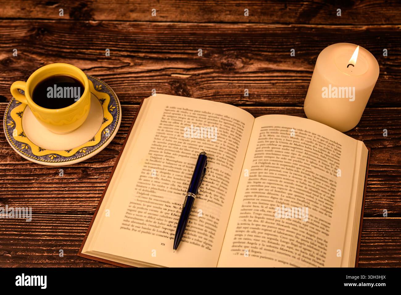 Natura morta superiore di un libro aperto con penna, tazza di caffè e lume di candela su legno rustico. Concetto di studio e scrittura con spazio di copia. Foto Stock