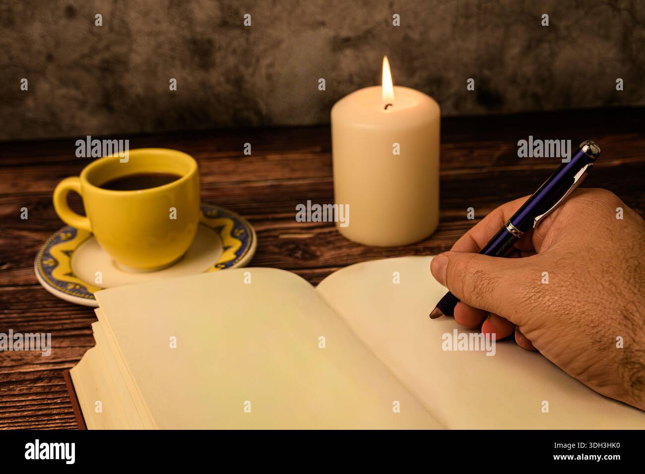 Primo piano di una scrittura a mano su una pagina vuota del notebook con caffè e lume di candela su legno rustico. Concetto di giornalismo, pianificazione e creatività. Foto Stock
