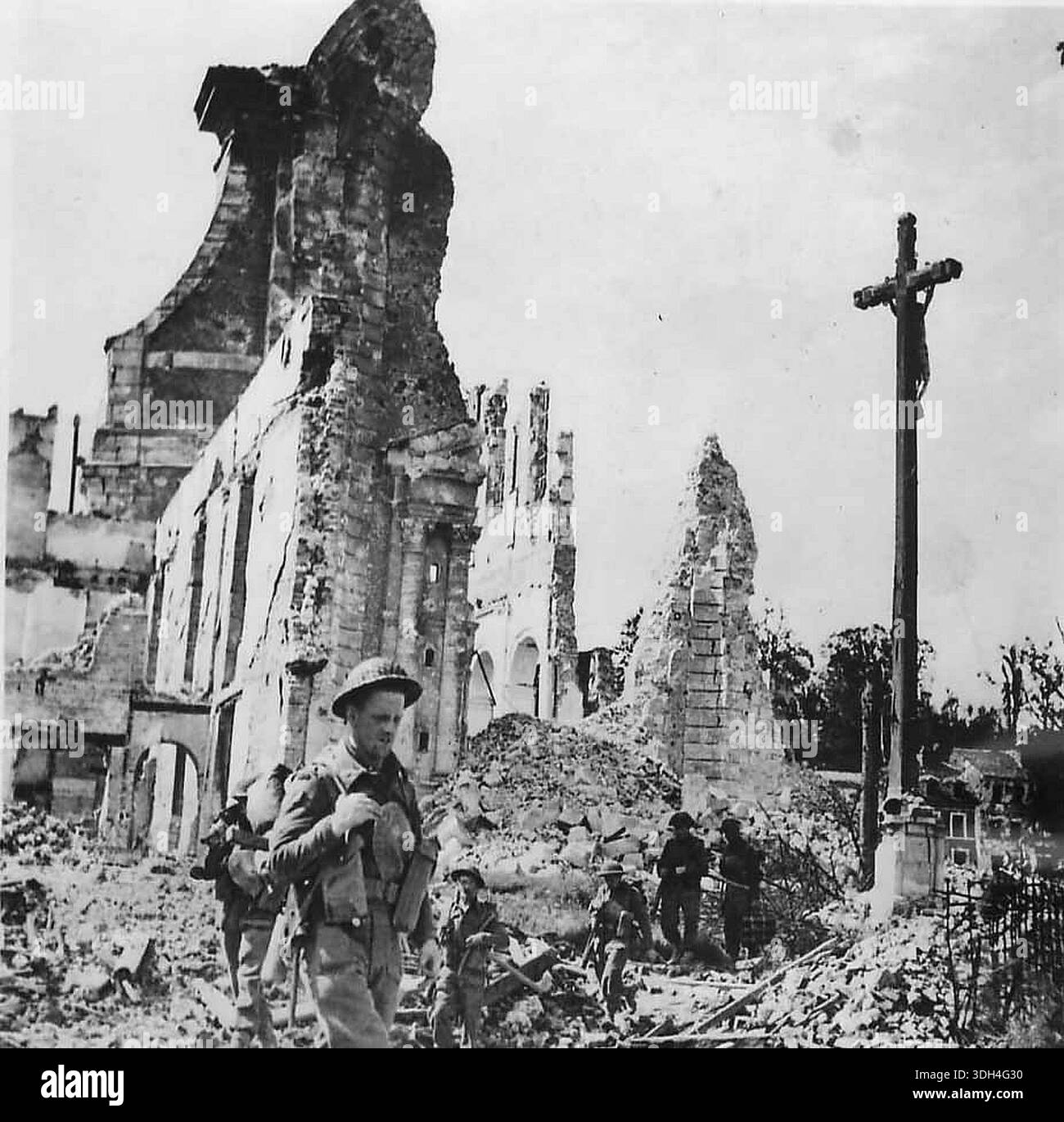 I soldati britannici passano i resti della chiesa di St Désir a Lisieux in Normandia. Il 6 giugno 1944 un'enorme forza d'invasione Alllied che coinvolgeva 7000 navi e 140.000 uomini sbarcò con successo sulla costa francese e stabilì cinque teste di spiaggia. Una campagna di inganno di successo significò che gran parte della resistenza tedesca si trovava a Calais e le perdite furono relativamente poche per le dimensioni e i rischi dell'operazione. Foto Stock
