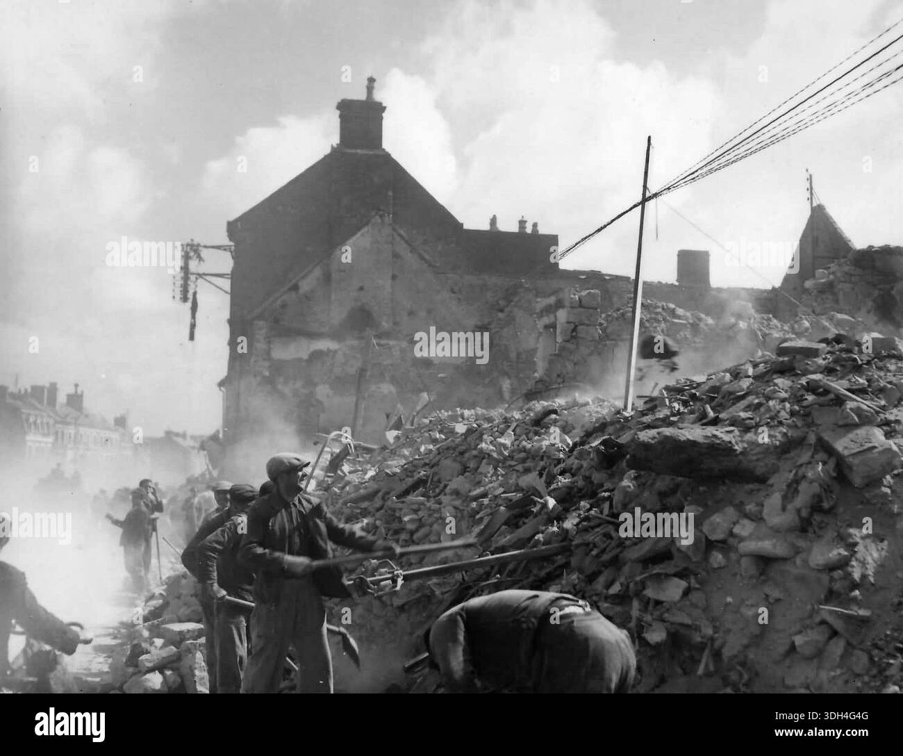 I francesi scavano tra le macerie di Isigny dopo il D-Day. Il 6 giugno 1944 un'enorme forza d'invasione Alllied che coinvolgeva 7000 navi e 140.000 uomini sbarcò con successo sulla costa francese e stabilì cinque teste di spiaggia. Una campagna di inganno di successo significò che gran parte della resistenza tedesca si trovava a Calais e le perdite furono relativamente poche per le dimensioni e i rischi dell'operazione. Foto Stock
