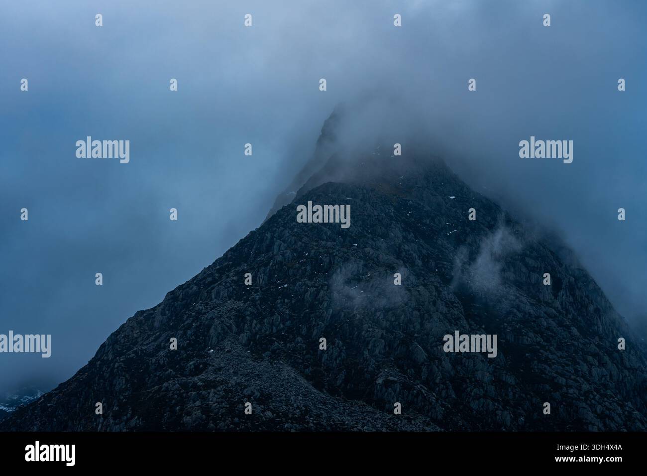 Vetta rocciosa del Tryfan parzialmente oscurata da nuvole basse in Snowdonia Foto Stock
