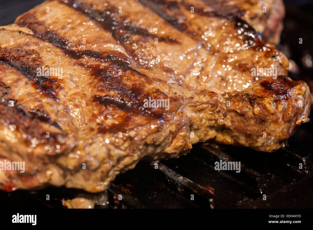 cuocere bistecca di manzo biologica su uno sfondo di piastra in padella di ghisa. Foto Stock