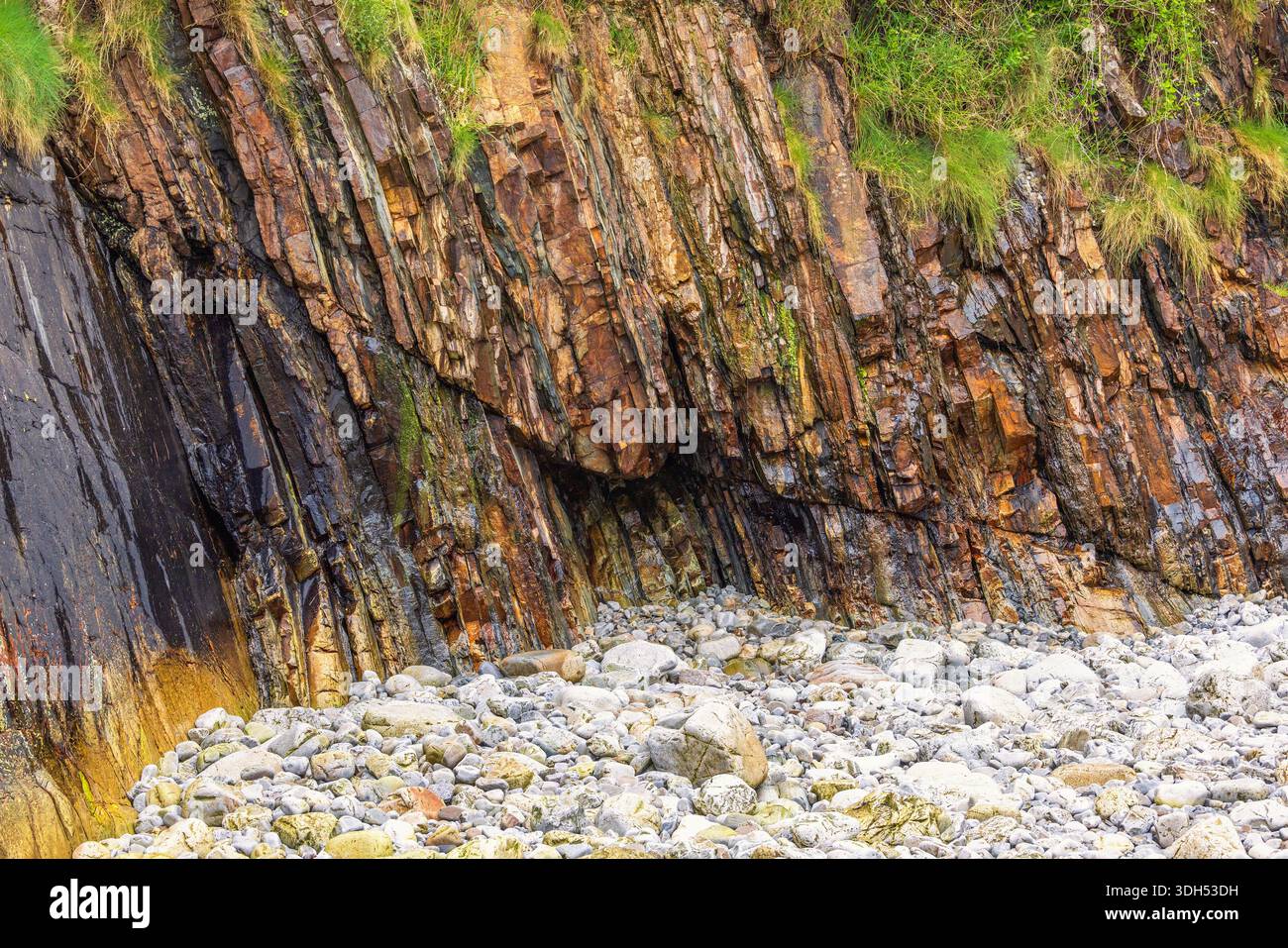 Spiaggia rocciosa con motivi naturali sulla roccia bagnata Foto Stock