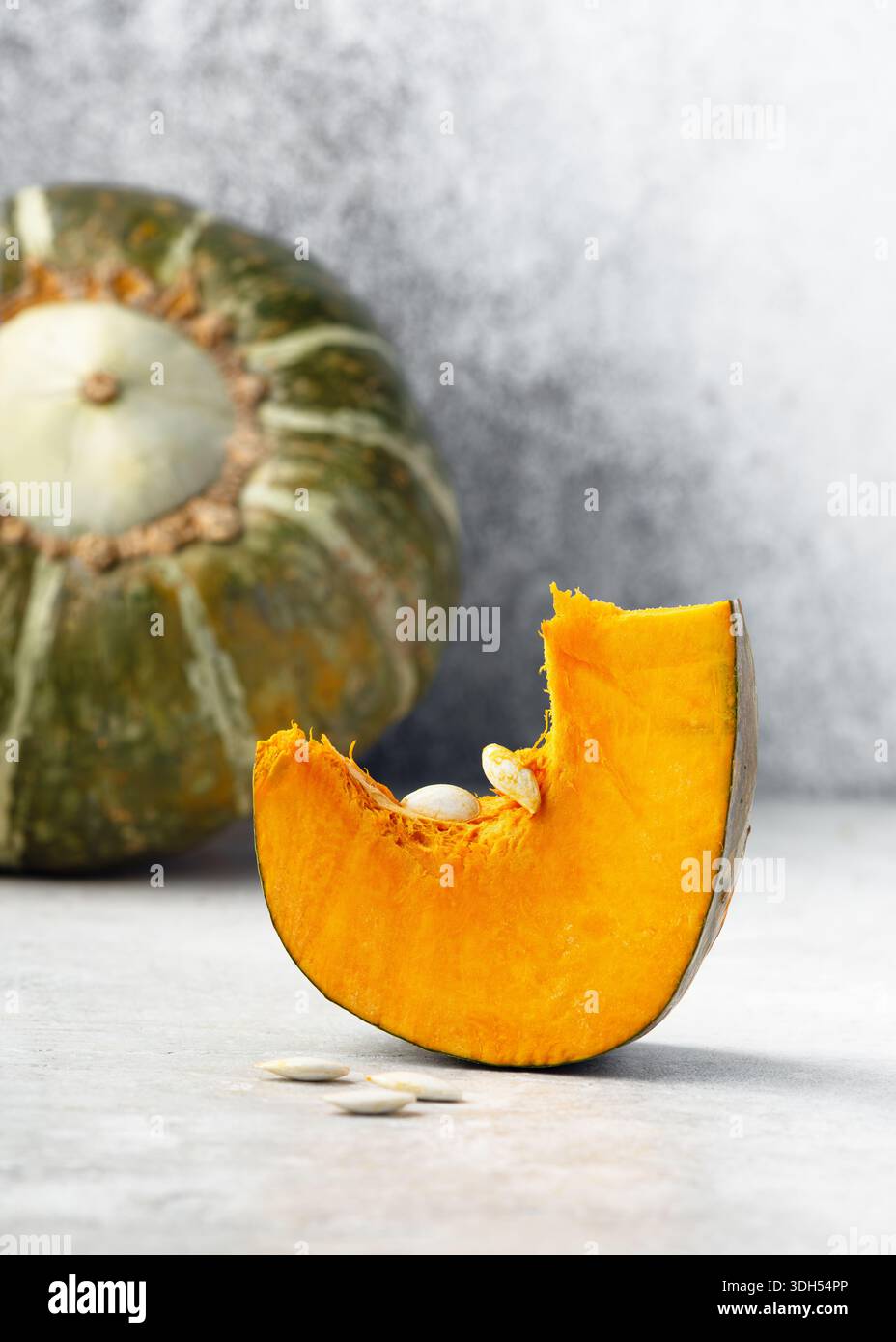 Fresco squash Cabocha invernale "Burgess Buttercup" mostrato intero e tagliato a fette. Crosta verde scuro con strisce chiare e interni di colore arancione intenso. Foto Stock