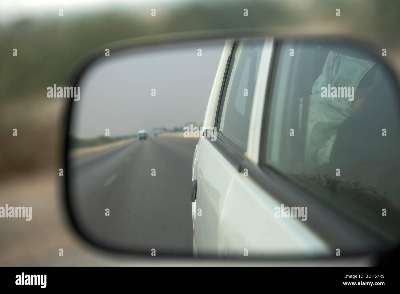 Karachi, Pakistan - 14 dicembre 2025: Guarda nello specchietto retrovisore di un'auto. Vista posteriore dello specchietto per auto Foto Stock
