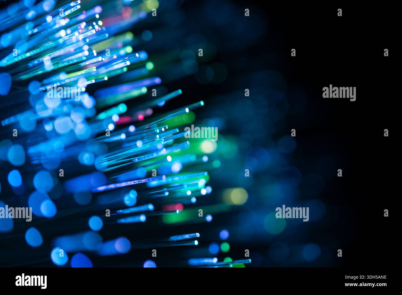Primo piano di cavi in fibra ottica che emettono una brillante luce blu e verde con un accattivante effetto bokeh. Lo sfondo astratto è futuristico e di Foto Stock