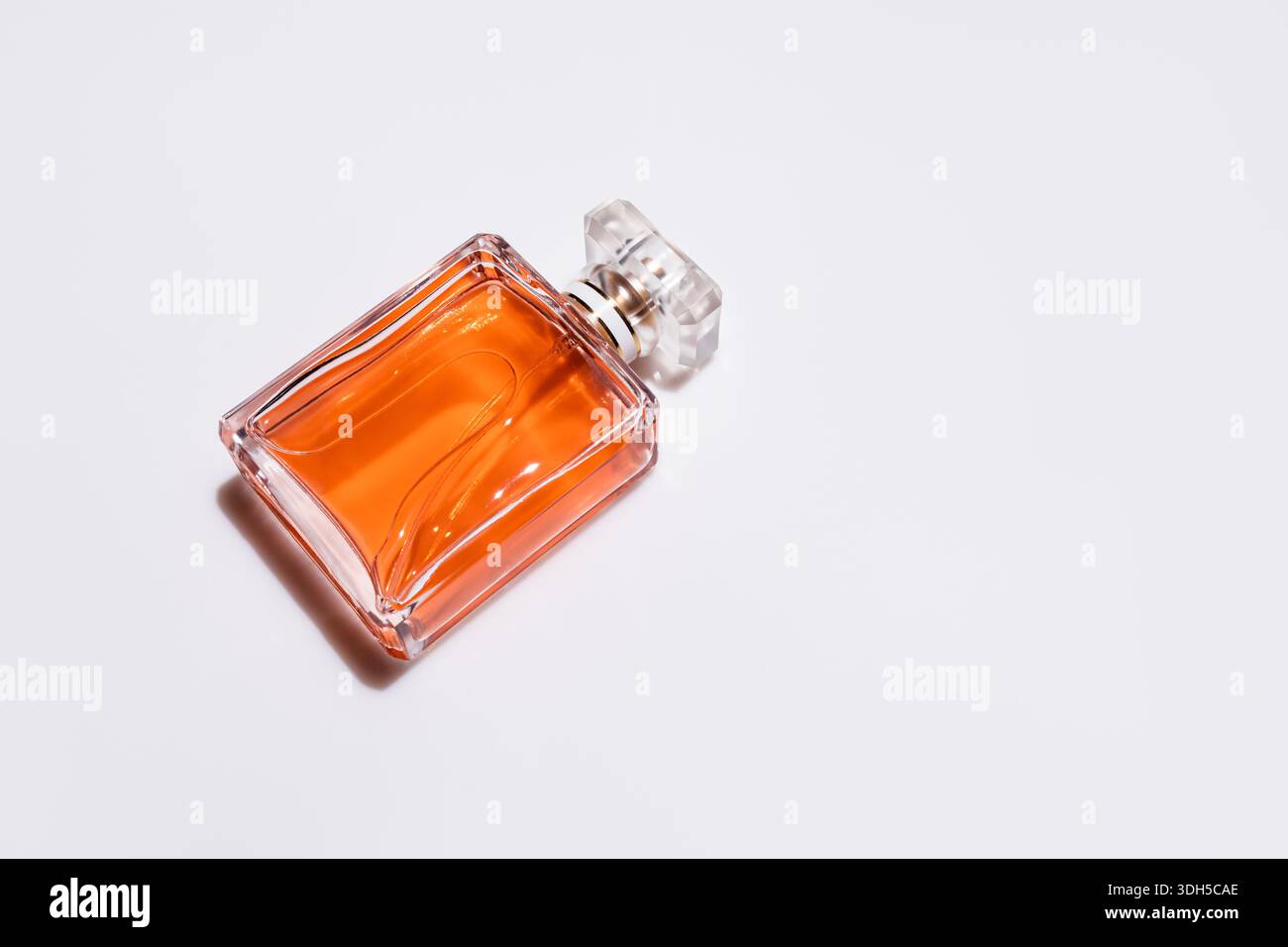 Una sofisticata bottiglia di profumo in vetro riempita di liquido ambrato poggia elegantemente su una superficie in marmo lucido. La scena trasuda lusso e raffinatezza, ciao Foto Stock