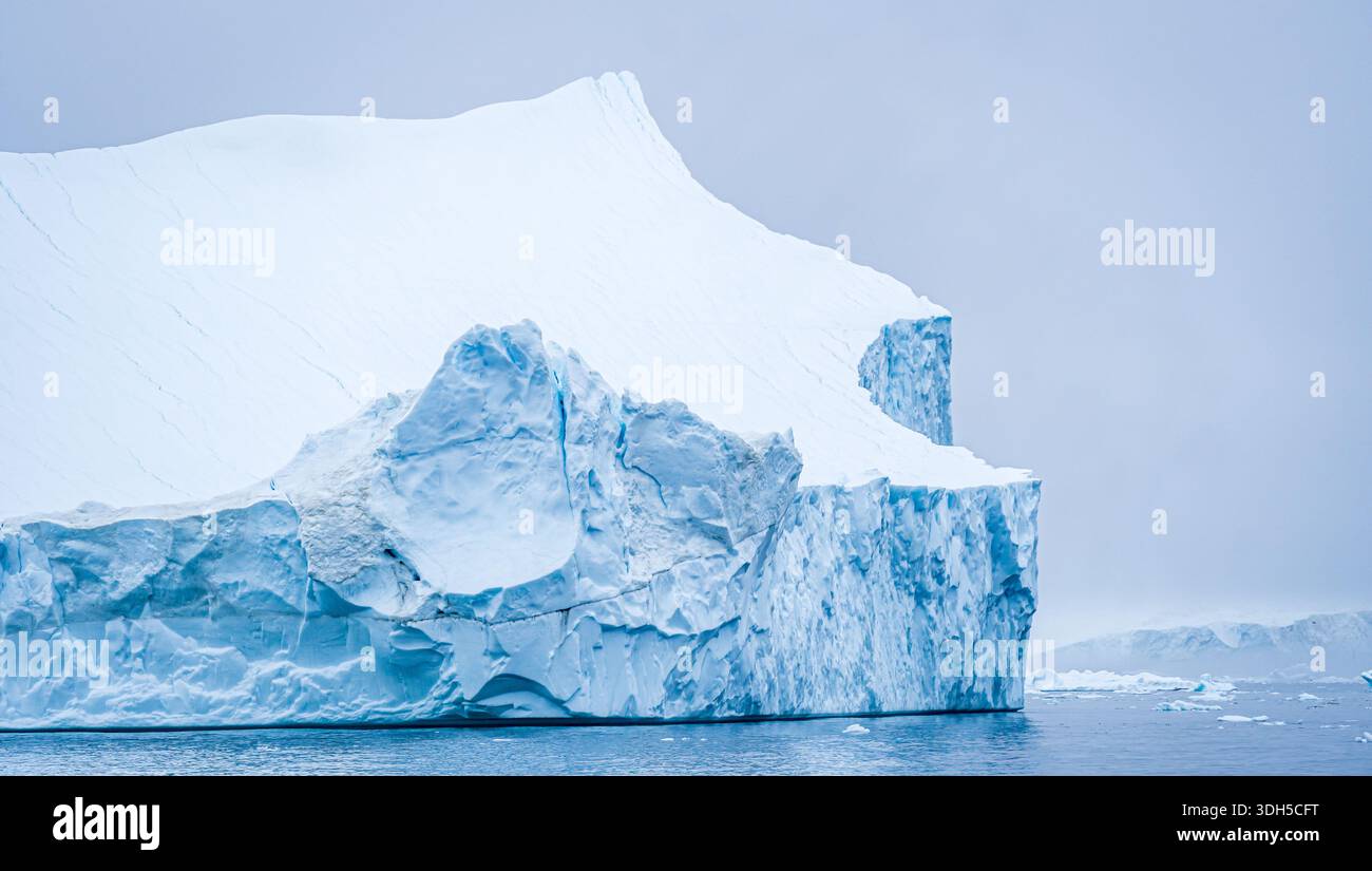 Un iceberg torreggiante con texture intricate sorge dalle fredde acque della Groenlandia, mostrando la splendida e aspra bellezza del selvaggio ghiacciato dell'Artico Foto Stock