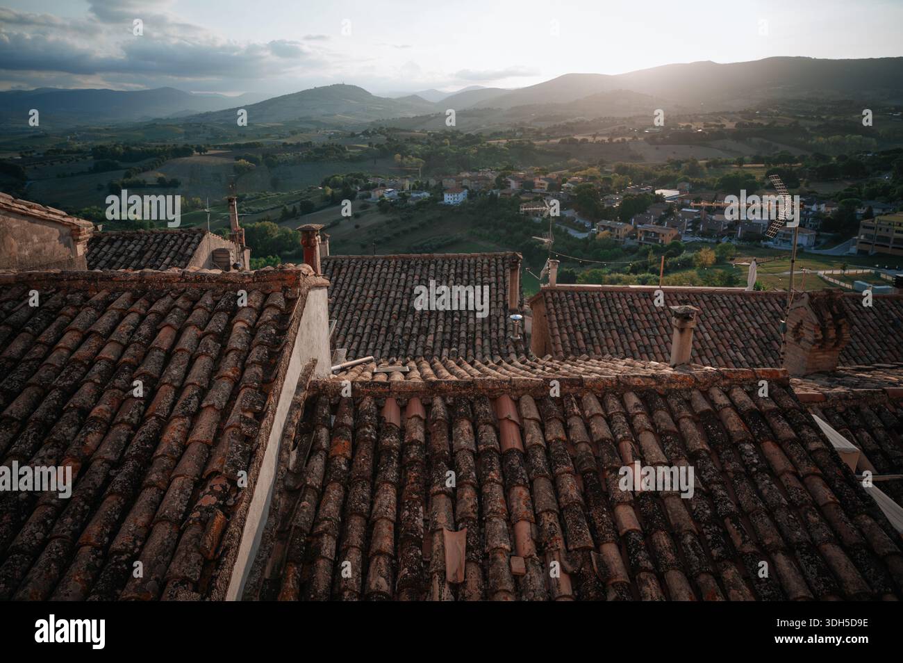 Vista aerea di un'incantevole cittadina italiana con tetti rustici e lussureggiante campagna verde. Questa fotografia con drone cattura la bellezza serena Foto Stock