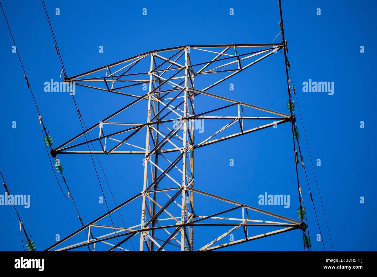 Primo piano di una torre di trasmissione a reticolo in acciaio che trasporta linee elettriche ad alta tensione con isolanti in ceramica, che rappresentano violazioni della distribuzione di elettricità Foto Stock