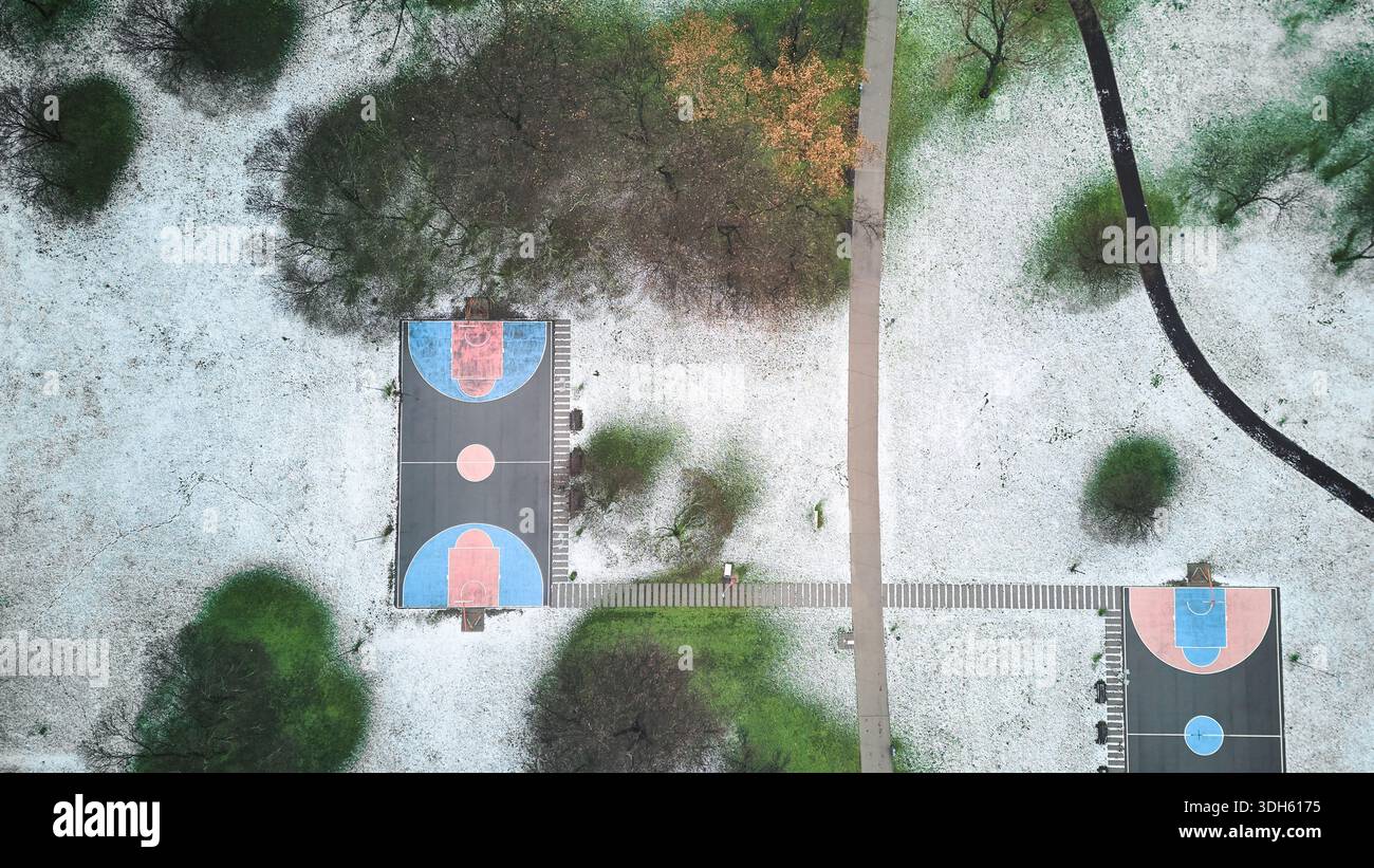 Vista sul campo da pallacanestro all'aperto e sul parco coperto di neve Foto Stock