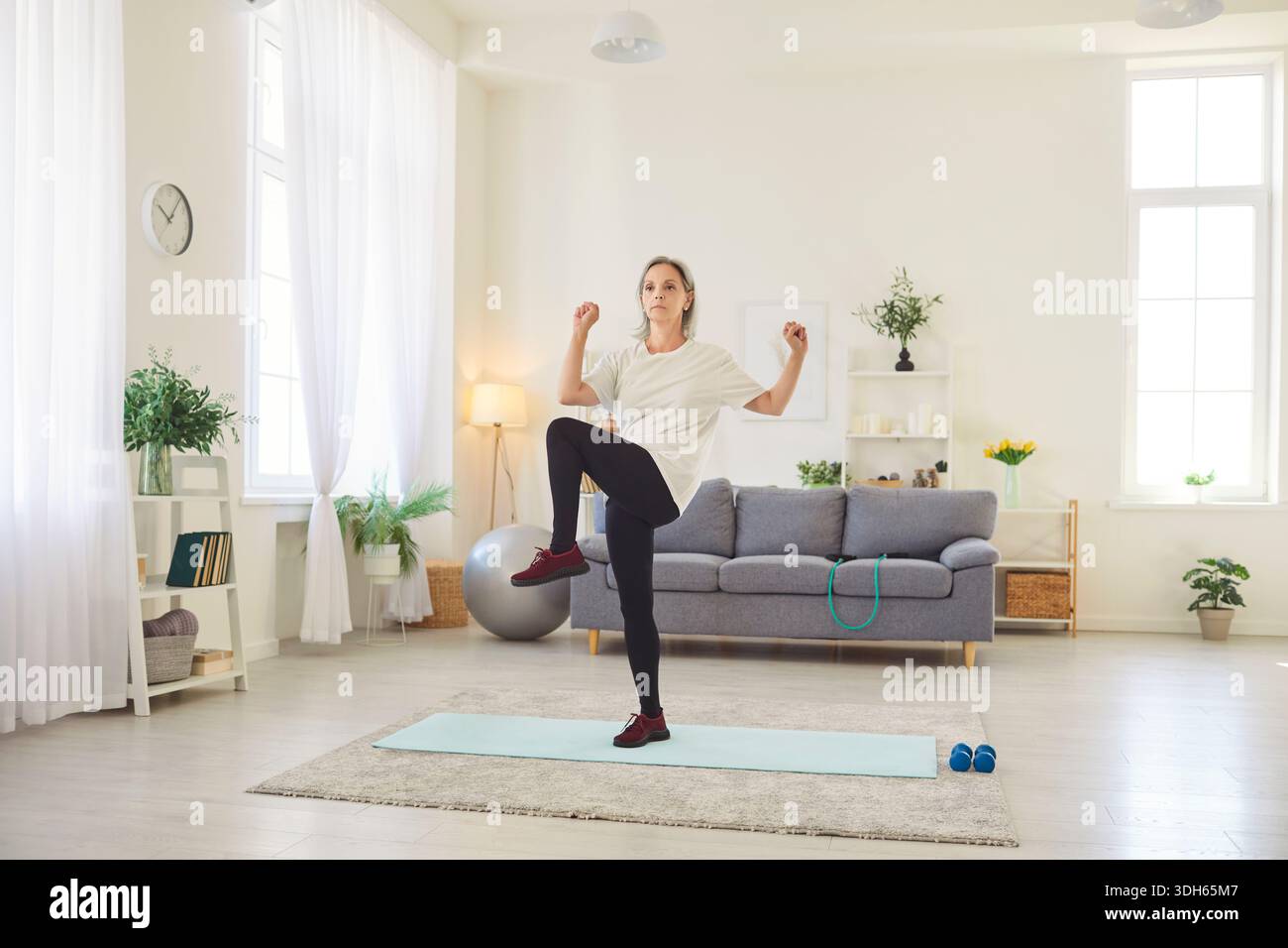 Donna anziana che fa esercizi di stretching a casa per il fitness e la salute Foto Stock