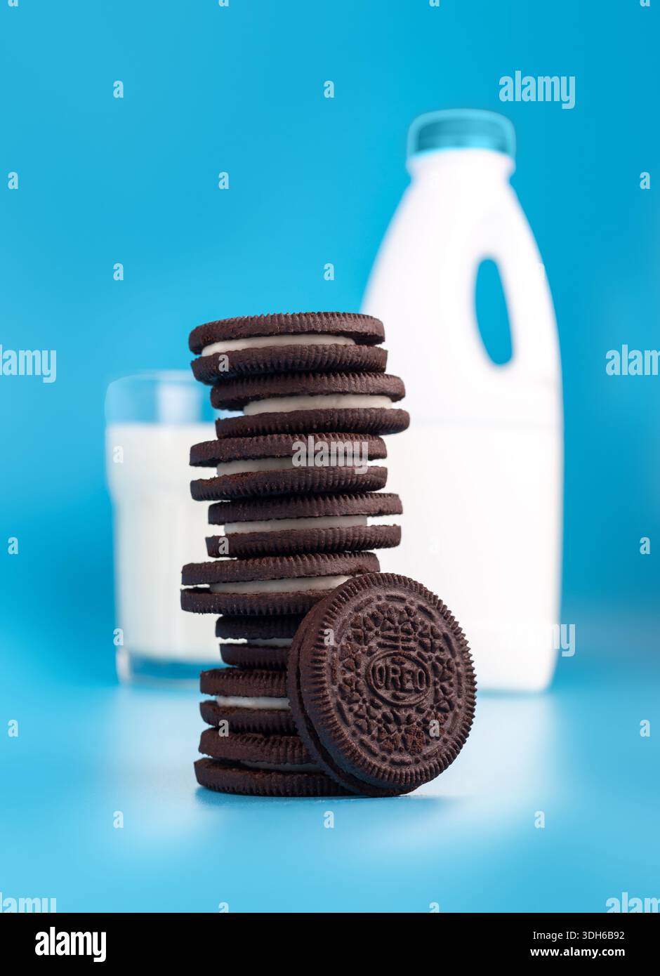 Horishni PlavniUkraine - 21 agosto 2022: Biscotti OREO in pila con un bicchiere di latte fresco su sfondo blu (famosa marca americana di biscotti) Foto Stock