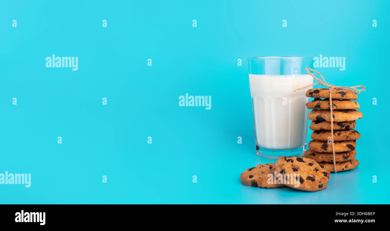 Bicchiere di latte fresco e biscotti scuri a base di cioccolato su sfondo blu Foto Stock