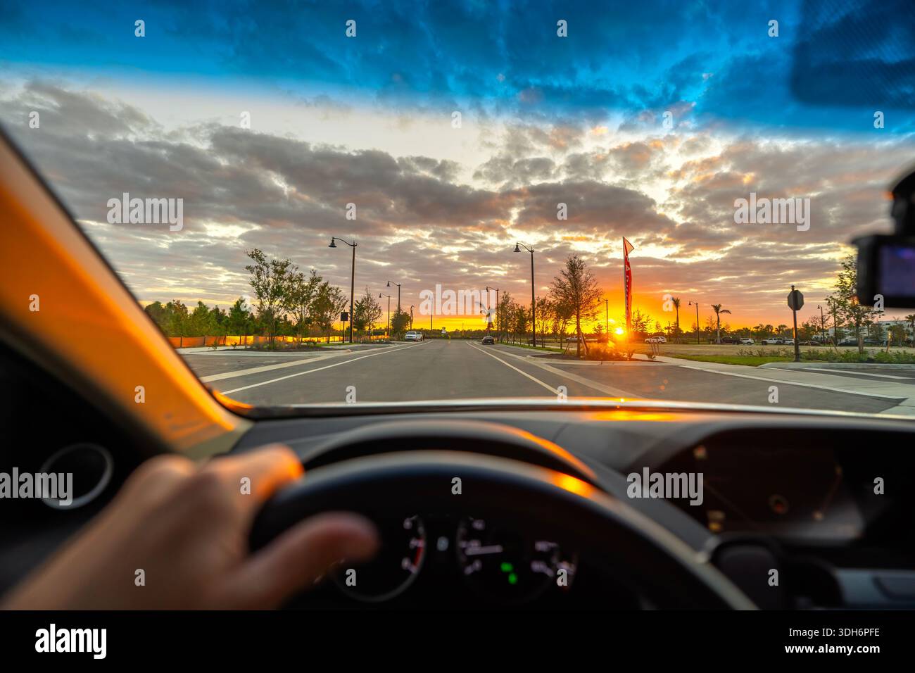 Viaggio in auto POV attraverso una città della Florida, con parabrezza che incornicia la strada e il traffico serale creando una dinamica scena suburbana. Foto Stock
