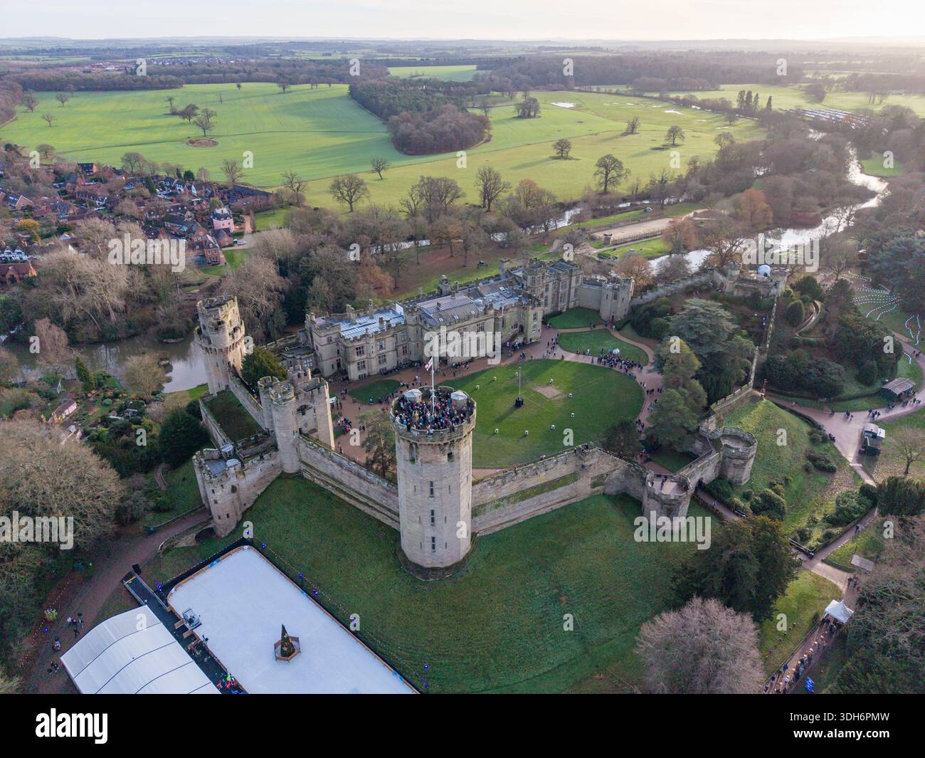 Vista aerea dell'imponente castello di Warwick, con le sue antiche mura in pietra che contrastano con i vivaci campi verdi e il tortuoso fiume Warwick, Inghilterra, Foto Stock