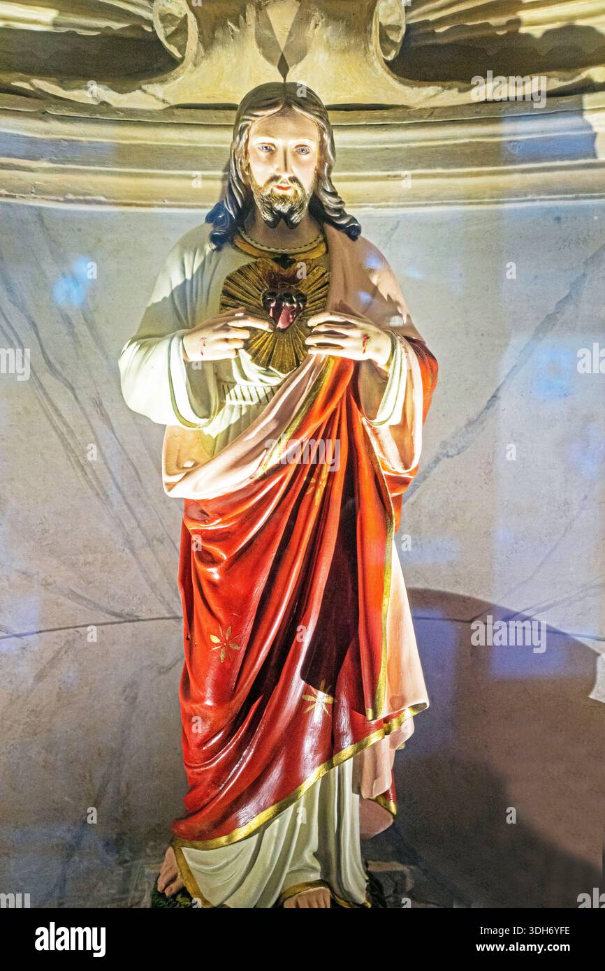 Statua di Gesù Cristo in un mantello rosso illuminato dal sole. Festa religiosa. Foto Stock