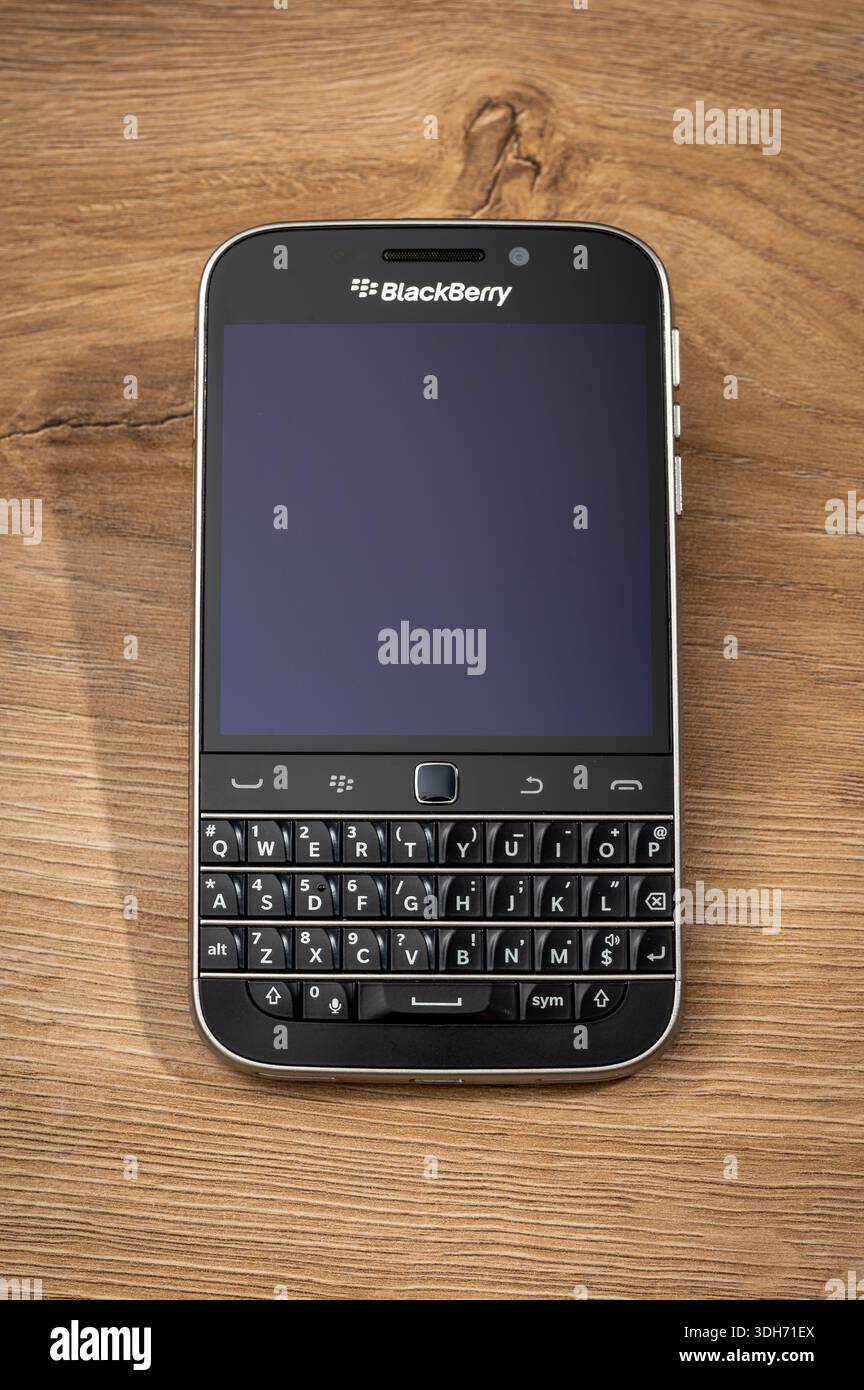 Milano, Lombardia, Italia - 16 gennaio 2026: Smartphone BlackBerry Q20 con tastiera fisica appoggiata su un caldo sfondo in legno Foto Stock