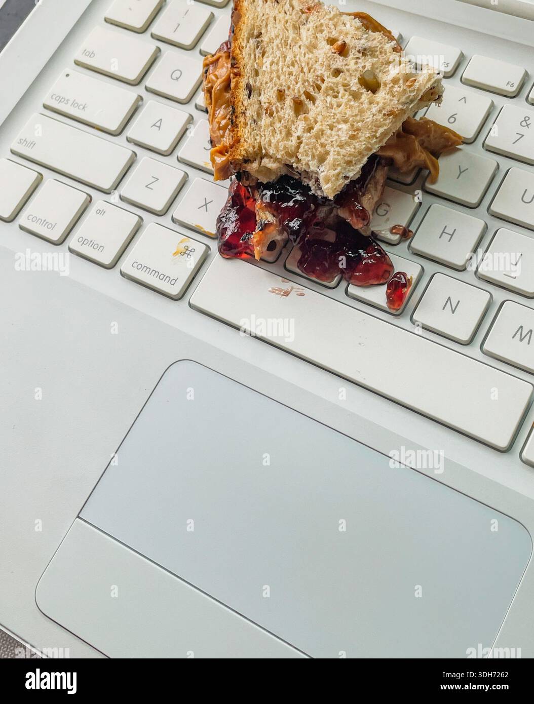 Primo piano di un sandwich di burro di arachidi e gelatina versato sulla tastiera di un computer, 2026, Stati Uniti - Immagine stock catturata con smartphone